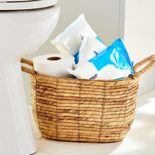 Flushable wet wipes in blue and white wrappers in a wicker basket by a toilet