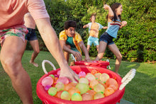 Assorted self-sealing water balloons floating in a red inflatable pool