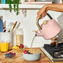 Rose ceramic stovetop tea kettle pouring hot water from spout