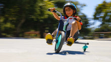 Teal mini 3-wheel tricycle with black seat, shown outdoors while riding