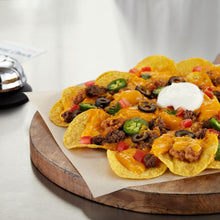 Tortilla chips with queso, black olives, jalapeños, and diced tomatoes on board