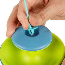 Hand pressing the blue top of a blue and lime electronic cat toy with feather wand.