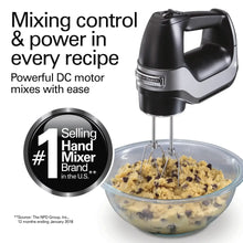 Black electric hand mixer with wire beaters over a clear mixing bowl