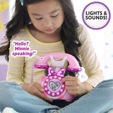 Child holding pink Minnie-style rotary phone toy with heart light panel
