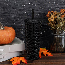 Black textured plastic insulated tumbler with straw, close front view of diamond texture.