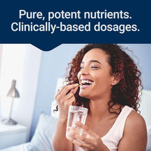 Woman holding a capsule near her mouth while drinking from a glass.