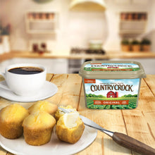 Country Crock Original buttery spread tub beside bread rolls on a wooden table.