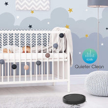 Black robot vacuum cleaner on floor near a baby crib with quieter cleaning indicator