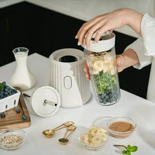 Sand white single serve blender with Tritan cup being lifted for blending