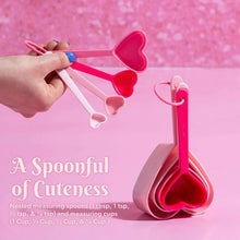Pink heart-shaped measuring spoons with nested cups and a matching spoon rest