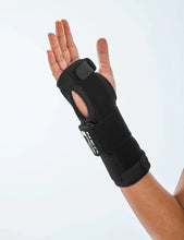 Black wrist brace worn on the wrist with palm facing up