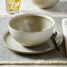 Cream stoneware soup bowl with matching saucer and spoon, gold-tone rim