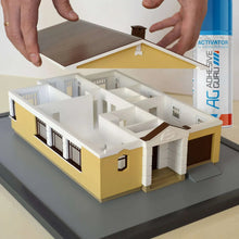 Cyanoacrylate glue bottle and activator spray applying adhesive to a model house