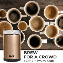 Electric coffee grinder in copper with clear lid, next to coffee cups