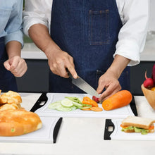 White plastic cutting boards with black handles, used for slicing vegetables and meat