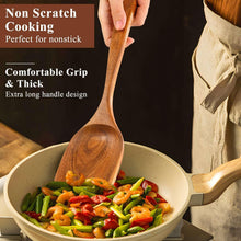 Wooden spoon stirring vegetables in nonstick pan, long handle and rounded bowl.