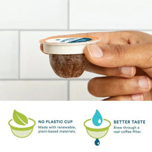 Hand holding a brown coffee pod with a tan plastic rim