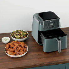 Sage air fryer with open basket on countertop, beside bowls of cooked food.