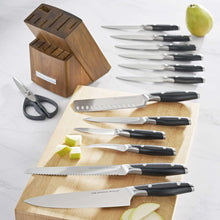 Assorted kitchen knives with black handles, wooden knife block, and kitchen shears on board
