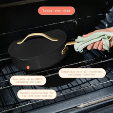 Black ceramic sauté pan with strainer lid on oven rack, gold-tone handles