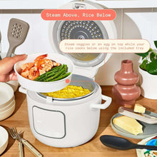 White electric rice cooker with lid open and inner steam tray, with vegetables and rice