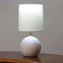 Mini table lamp with light fabric shade and textured ball base on a tabletop