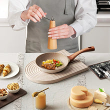 Nonstick frying pan with speckled brown interior and wood handle on serving board