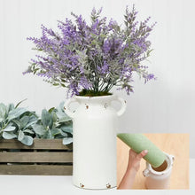 Green foam vase insert being placed into a white vase with flowers