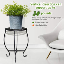 Black round metal plant stand holding a gray pot with leafy plant.