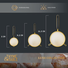 Three fine mesh strainers in different sizes with gold rims and dark handles