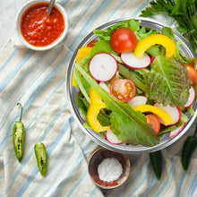 Stainless steel salad bowl with mixed greens and sliced vegetables