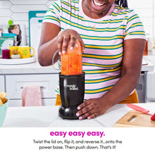 Black personal blender on countertop with clear blending cup filled with orange smoothie