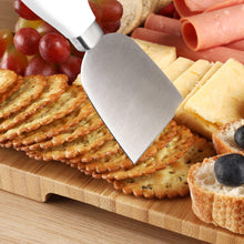 Stainless steel cheese knife with white handle on bamboo serving board with cheese slices