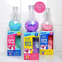 Three bath potion bottles with blue, purple, and pink contents in front of boxes.