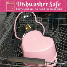 Pink heart-shaped Dutch oven on dishwasher rack, gold heart knob visible