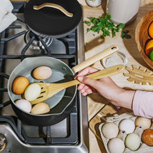 Ceramic nonstick covered sauce pan with lid, dark finish and gold-tone handle on stove