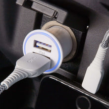 White 2-port car charger plugged in car socket with Lightning and USB-A cables.
