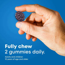 Hand holding dark gummy pieces, One A Day Men’s Multi gummy supplement