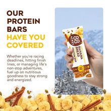 Wrapped banana bread protein bar held in hand with crumbs and banana slice pieces
