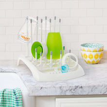 White drying rack holding bottles and accessories, with green cup and bottle