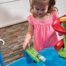 Child using green water chute and red spout on a blue kids water table