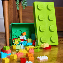 Green LEGO DUPLO storage box open with assorted colorful bricks on floor