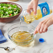 Vegetable oil bottle pouring into a glass bowl while whisking