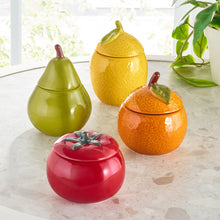 Yellow ceramic lemon candle with lit wick, leaf-topped lid beside it