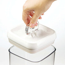 Hand pressing latch on white flip lid of a clear square food container