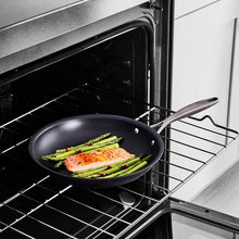 Black non-stick fry pan in an oven with vegetables