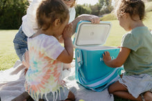 Igloo hard side cooler held open by a person, turquoise blue