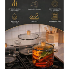 Clear glass pot on gas range with metal lid and bamboo knob, cooking with vegetables inside.