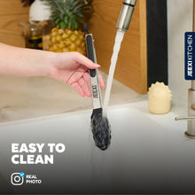 Kitchen tongs with silicone tips being rinsed under a faucet
