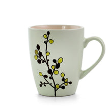 Green stoneware mug with floral branch motif in black and yellow-green